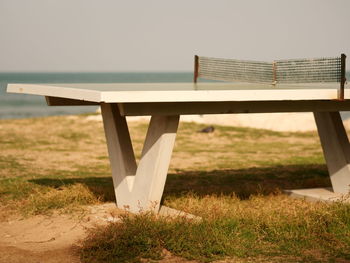 Wooden table on field against clear sky