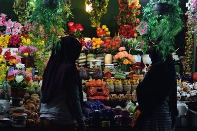 Women looking at crockery and flower decorations at market stall