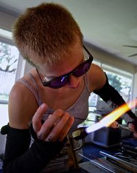 Young woman making glass with flaming torch in factory