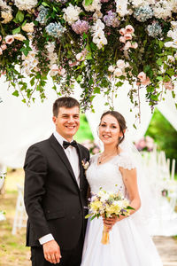 Portrait of smiling couple standing against plants