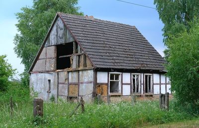 Exterior of abandoned house on field against sky