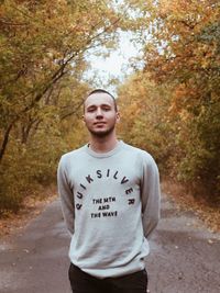 Portrait of man standing on road in autumn