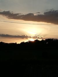 Silhouette trees on field against sky at sunset