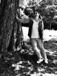 Portrait of woman standing on tree trunk