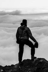 Man looking at rock against sky