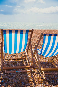 Close-up of chairs on beach against sky