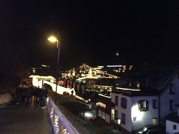 Illuminated city street against sky at night