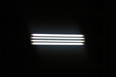 Low angle view of illuminated light on wall in darkroom