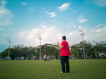 Rear view of men standing on field against sky