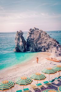 Woman standing by umbrellas on shore at beach