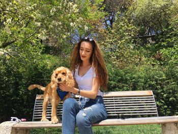 Young woman sitting with dog on bench at park
