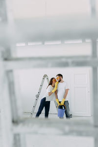 Happy smiling married couple engaged in renovation repair in the room of the house preparing to move