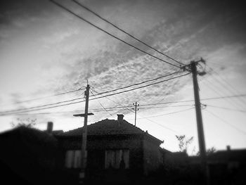 Low angle view of electricity pylon against cloudy sky