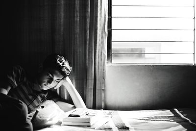 Teenage boy reading book in bedroom