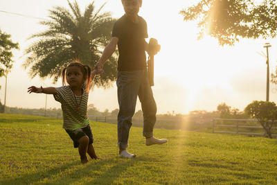 Rear view of mother and daughter walking on field