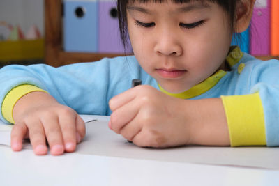 Close-up of girl drawing on book at home