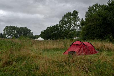 Tent on field by trees against sky