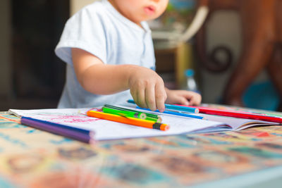 Midsection of boy drawing on table at home