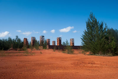 Trees on landscape against cloudy sky