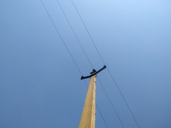 Low angle view of telephone pole against clear blue sky