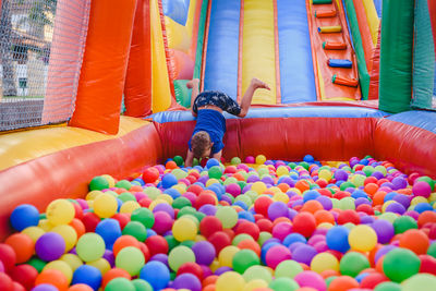 Full length of boy playing with multi colored balloons