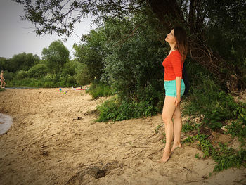 Side view of woman standing against trees