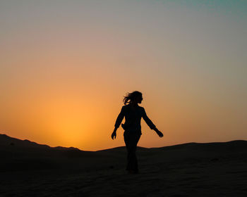 Silhouette man standing on mountain against sky during sunset