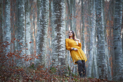 Low angle view of woman standing in forest during autumn