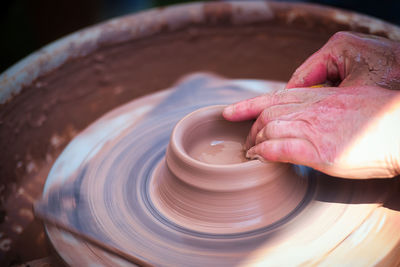 Cropped hand of person making pottery at workshop