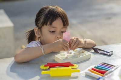 Close-up of cute girl playing with childs play clay at table outdoors