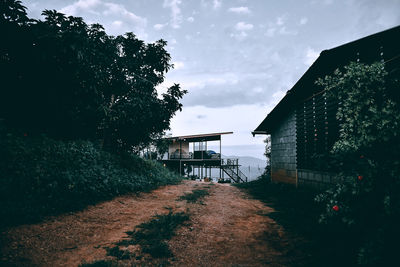 House by trees and buildings against sky