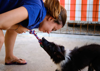 Side view of girl playing with dog