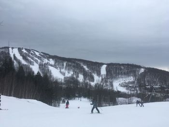 People on snowcapped mountain against sky