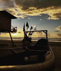 Boat moored on beach against sky during sunset