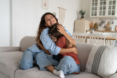 Young woman using phone while sitting on sofa at home