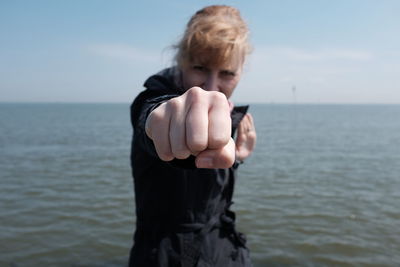 Portrait of young woman fighting stance against sea