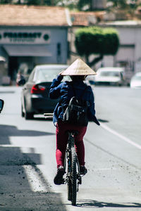 Rear view of person riding bicycle on road