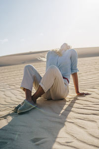 Woman sitting on sand at desert