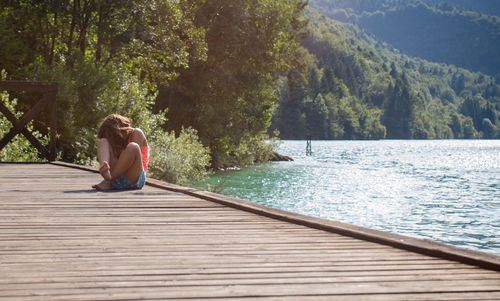 Full length of girl sitting by lake