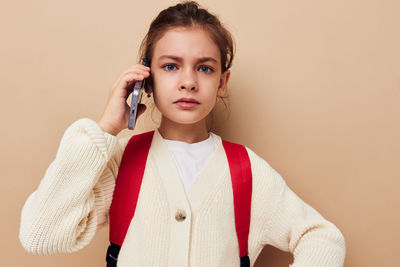 Portrait of young woman standing against pink background