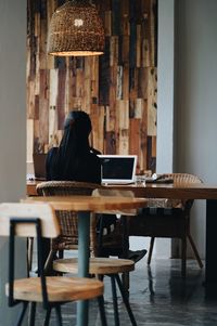 Rear view of woman sitting on chair at table