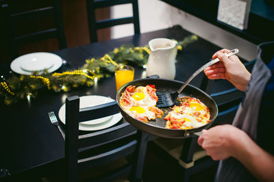 Midsection of woman serving food while standing by dining table at home