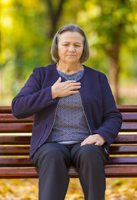 Woman with hand on chest sitting on bench