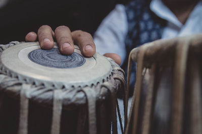 Midsection of man playing tabla against black background