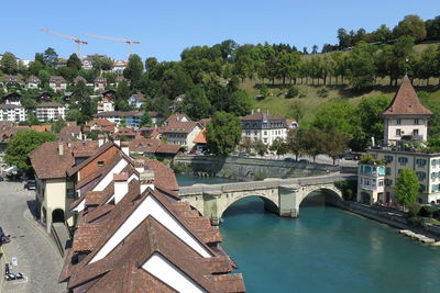 Bridge over river amidst buildings in town against sky