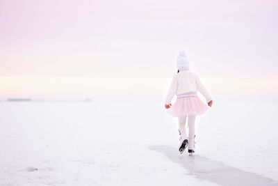 Little girl skating on ice in morning light at dawn. winter sports on natural background.