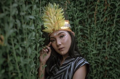 Portrait of beautiful young woman standing against plants