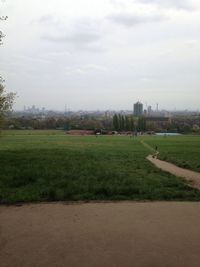 View of grassy field against cloudy sky