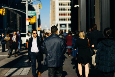 Rear view of people walking on city street