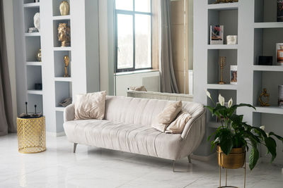 Stylish scandinavian living room with design grey sofa, furnitures,elegant personal accessories. 